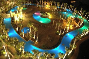 Relax by the freeform pool surrounded by palm trees, featuring a central island with a seating area.