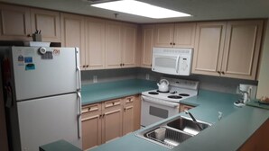 A compact kitchen with light wooden cabinets, a white refrigerator, a microwave, a stove, and a sink. - Seawatch 2BR/2BA South Tower Ocean View Condo - Fantastic Resort Myrtle Beach SC (Myrtle Beach)