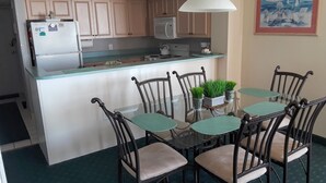 A compact kitchen with a central island, a dining area with four chairs, and a painting on the wall. - Seawatch 2BR/2BA South Tower Ocean View Condo - Fantastic Resort Myrtle Beach SC (Myrtle Beach)