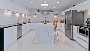 Een moderne keuken met witte kasten, een centraal eiland en een roestvrijstalen koelkast.