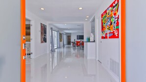 Een moderne hotelgang met een glanzende vloer, oranje accenten en moderne kunstwerken.
