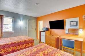 Una habitación de hotel con dos camas, un escritorio, una silla, un televisor y un refrigerador pequeño.