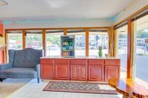 Una habitación con sofá, un armario de madera, un refrigerador y un ventanal con vistas al exterior.