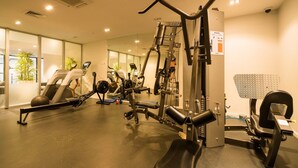 Un gimnasio con diversos equipos de ejercicio, incluyendo cintas de correr y máquinas de pesas, y un espejo grande en la pared.