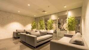 Una sala moderna con un sofá seccional, un sillón más pequeño y plantas en macetas.