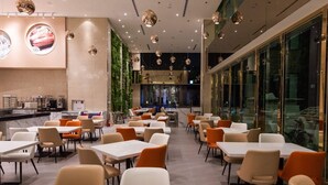 Ein modernes Restaurant mit mehreren Essbereichen, darunter eine Bar und ein Sitzbereich mit Tischen und Stühlen.