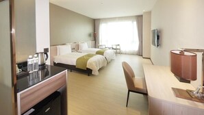 Ein Hotelzimmer mit Bett, Schreibtisch, Stuhl, Fernseher und einem Fenster mit Vorhängen.