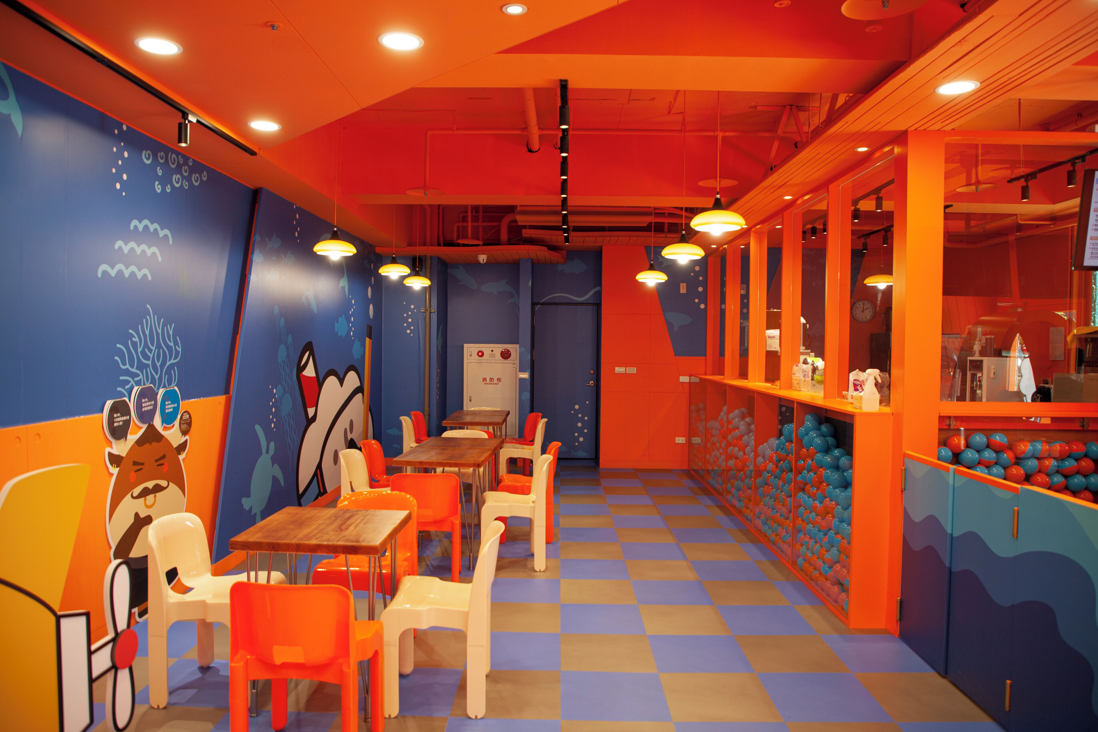 A brightly colored restaurant with orange and blue decor, checkered floor, and tables with white chairs.