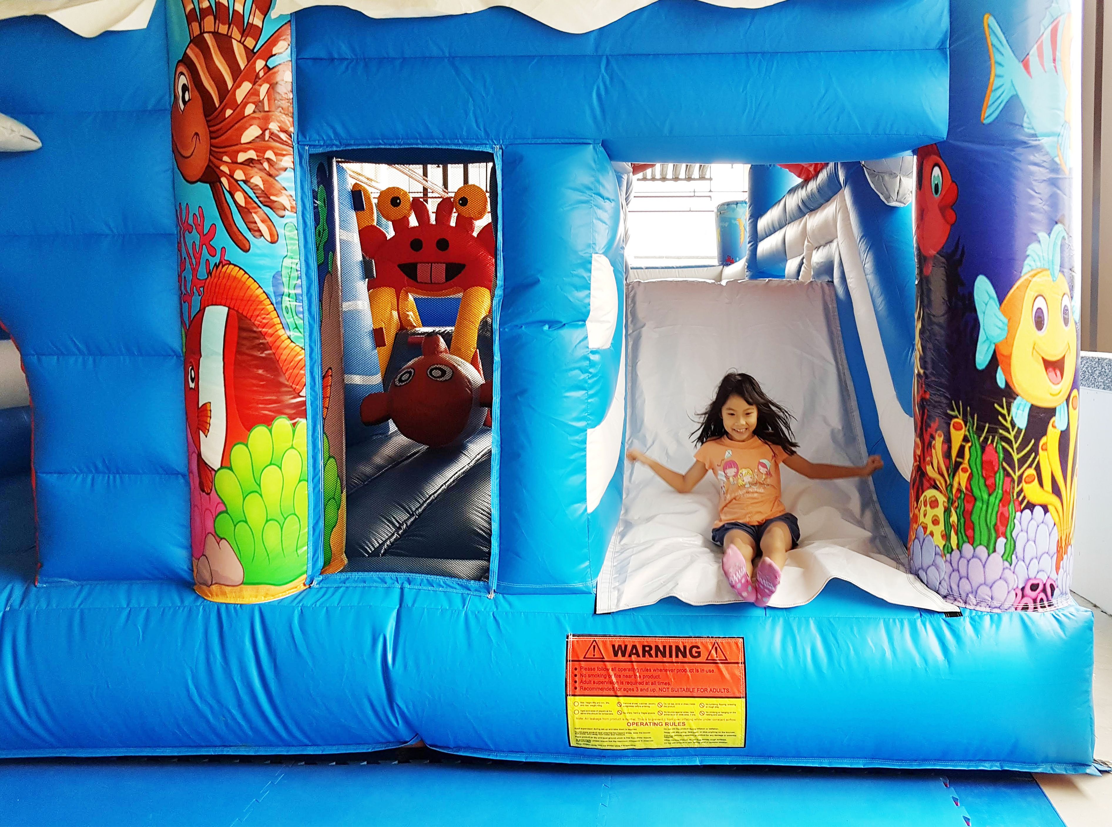 Un área de juego inflable con un tobogán, decorada con llamativos motivos marinos.