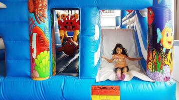 Un área de juego inflable con un tobogán, decorada con llamativos motivos marinos.