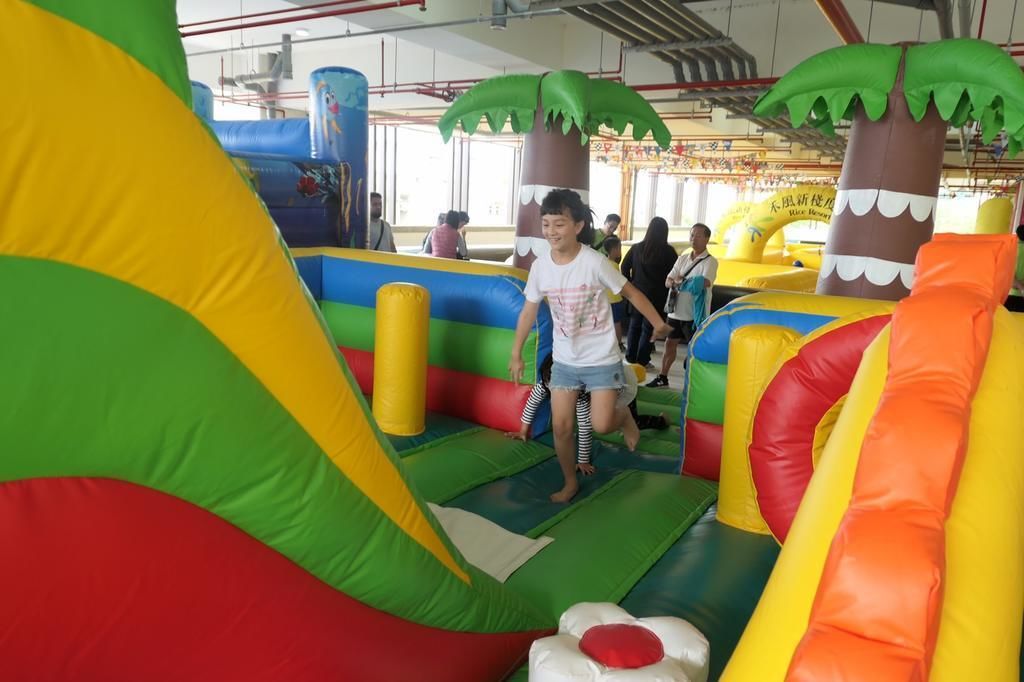Un área de juego inflable en el interior, con diversos colores y formas, incluyendo una estructura grande verde y amarilla y elementos inflables más pequeños.
