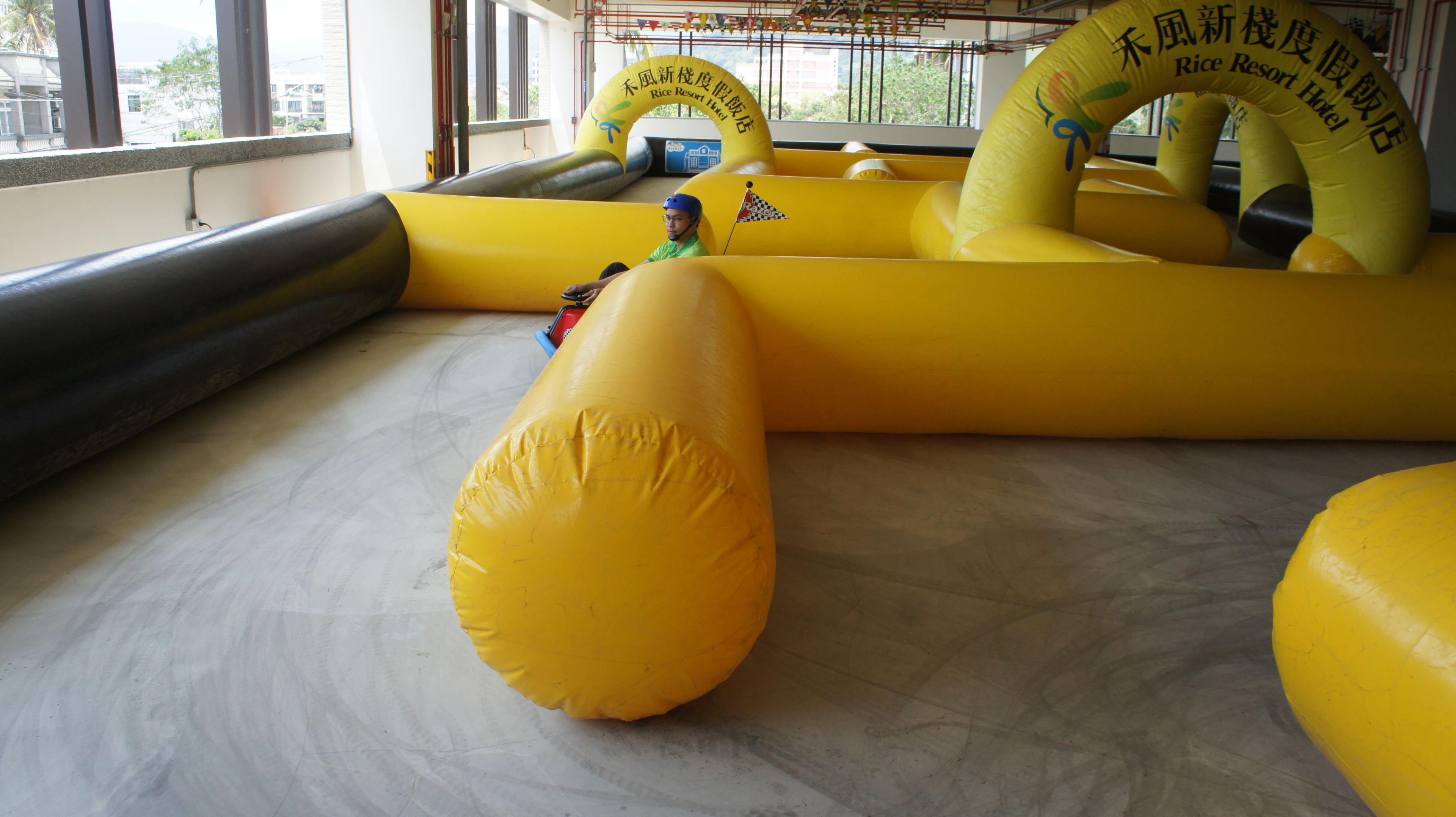 An indoor inflatable play area with a large yellow inflatable slide and a smaller inflatable structure with a flag.