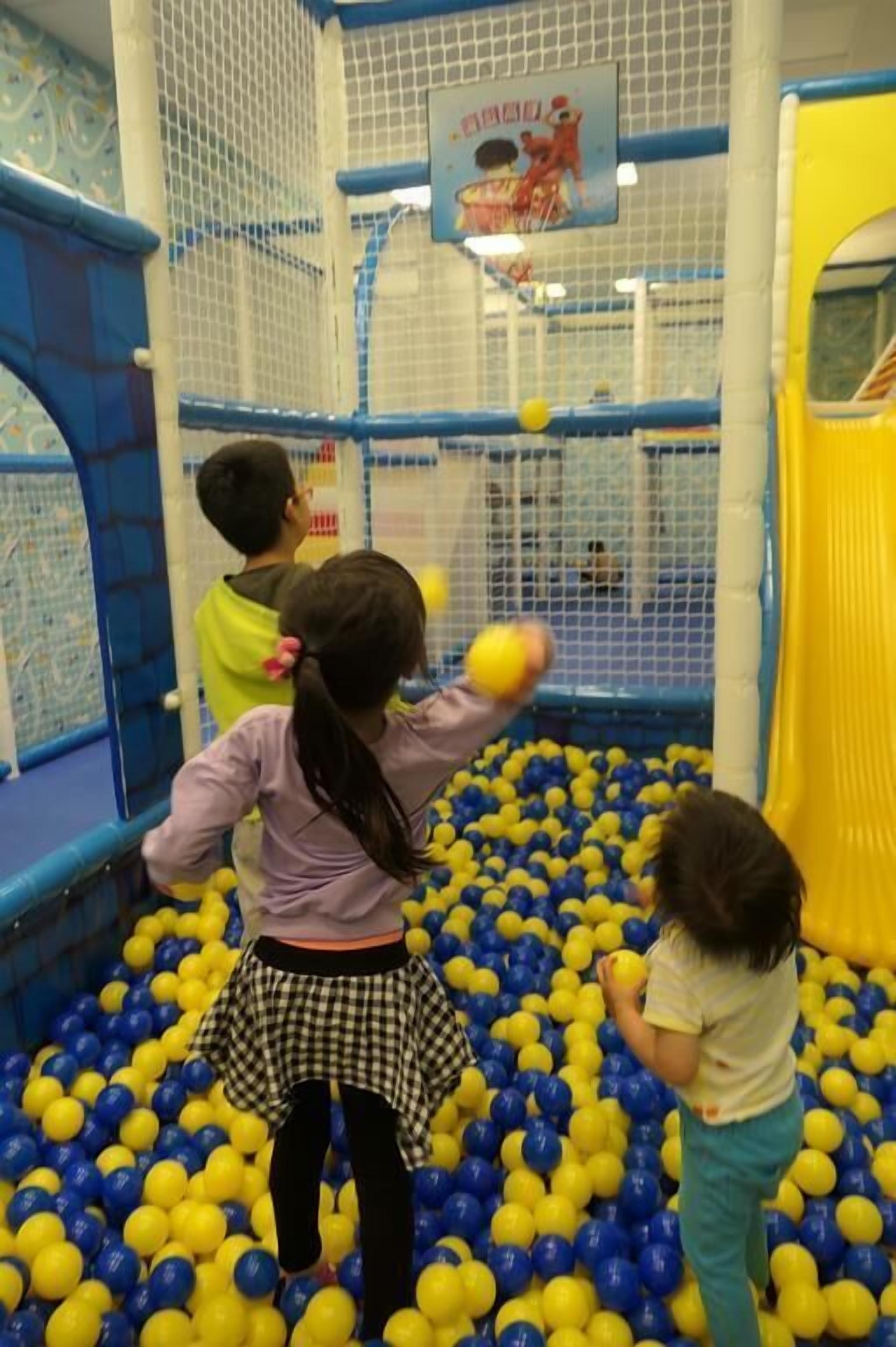 Niños jugando en un chapoteadero de pelotas con una estructura de red.