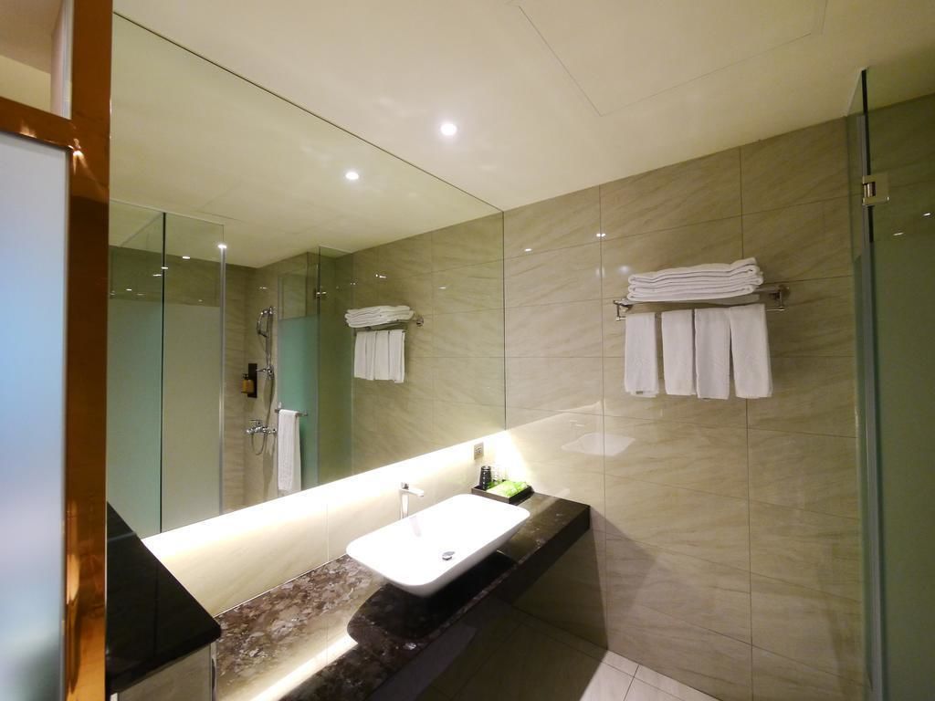 Une salle de bain moderne avec un grand miroir, un lavabo et une douche à parois de verre.