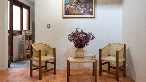 A room with two wicker chairs, a small table with a vase of flowers, and a framed painting on the wall. - La Casita del Abuelo, beautiful Oaxaca typical house  (San Felipe del Agua)