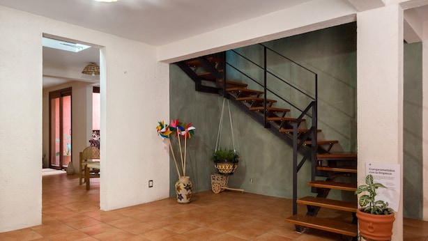 A spacious room with a tiled floor, a staircase with a metal railing, and a hanging light fixture. - La Casita del Abuelo, beautiful Oaxaca typical house  (San Felipe del Agua)