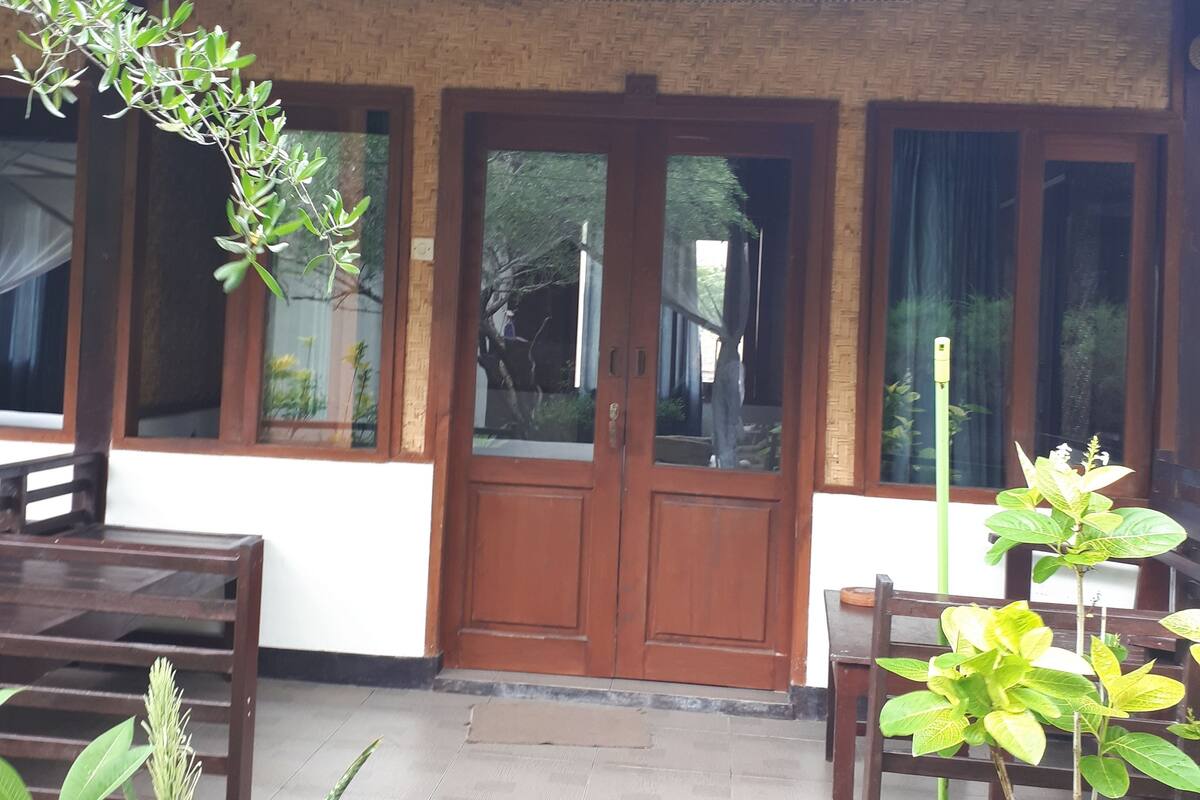 A building with a tiled entrance, wooden doors, and a tiled patio area with tables and chairs.