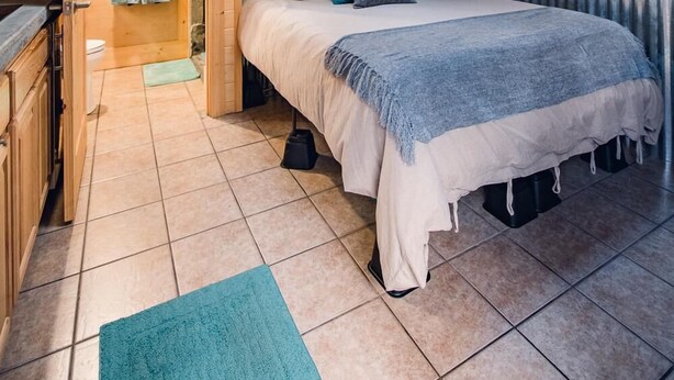 Ein Schlafzimmer einer Holzhütte mit Dachfenster, einem Bett, einem kleinen Schreibtisch und Blick ins Freie.