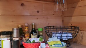Ein Holzregal mit verschiedenen Küchenutensilien, darunter Flaschen, eine rote Schüssel und ein Korb.