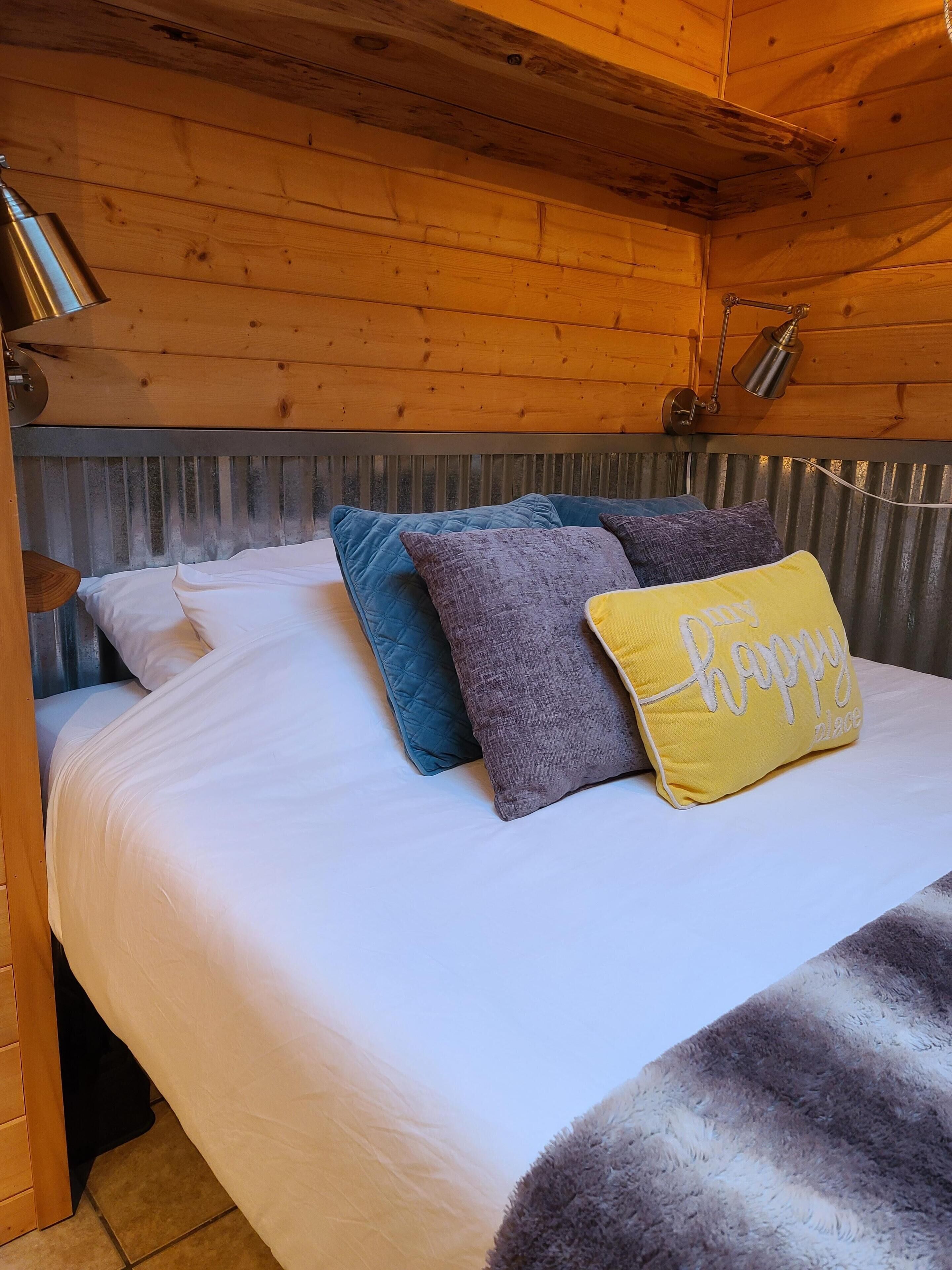 A wooden cabin bedroom with a bed, pillows, and a nightstand.