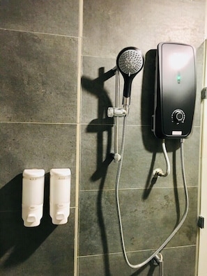 A shower area with a handheld showerhead, a wall-mounted control panel, and two white soap dispensers. - Enclave Business Hotel (Putrajaya)