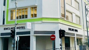 Un immeuble à plusieurs étages dont la façade est ornée d'une enseigne bien visible indiquant « ENCLAVE HOTEL ».
