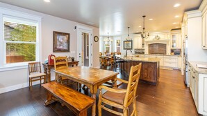 Una cocina amplia con armarios de madera, una isla grande y una zona de comedor con mesa y sillas de madera.