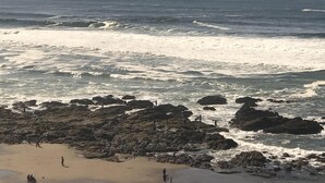 Une plage avec des affleurements rocheux et des vagues qui déferlent sur le rivage.