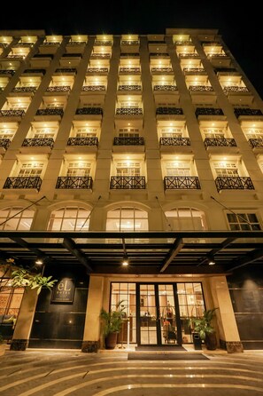 Un hotel con fachada moderna, varios balcones y una entrada bien iluminada.
