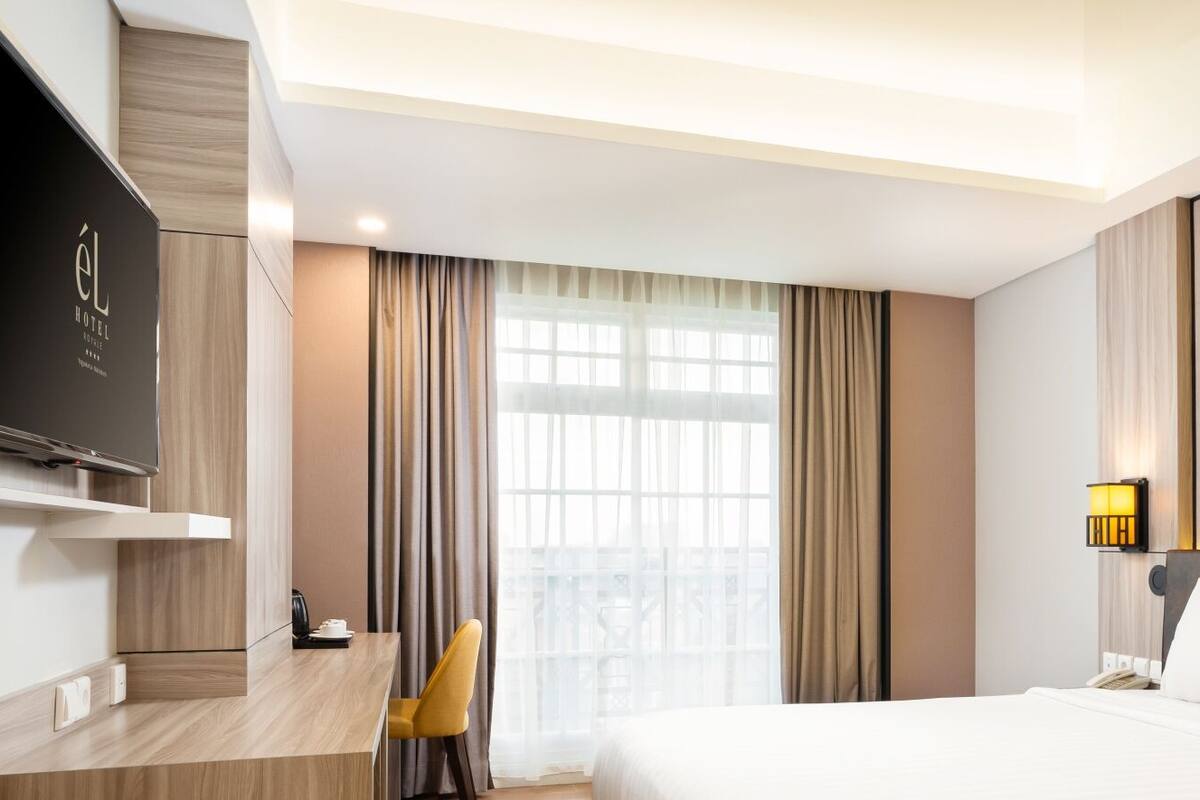 Une chambre d’hôtel avec un lit, un bureau, une chaise, une télévision et un tableau au mur.