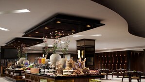En moderne hotellobby med en central receptionsdisk, et siddeområde og dekorative elementer som vaser og planter.