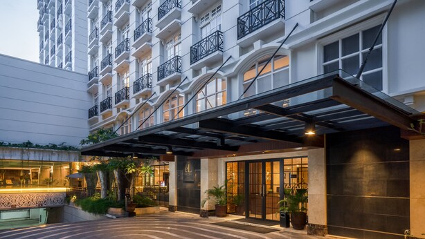 En hotelindgang med et overdækket gelænder, store vinduer og plantekasser.