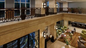 Et hotel lobby med en mezzanin, siddeområde og udsigt til det fri.