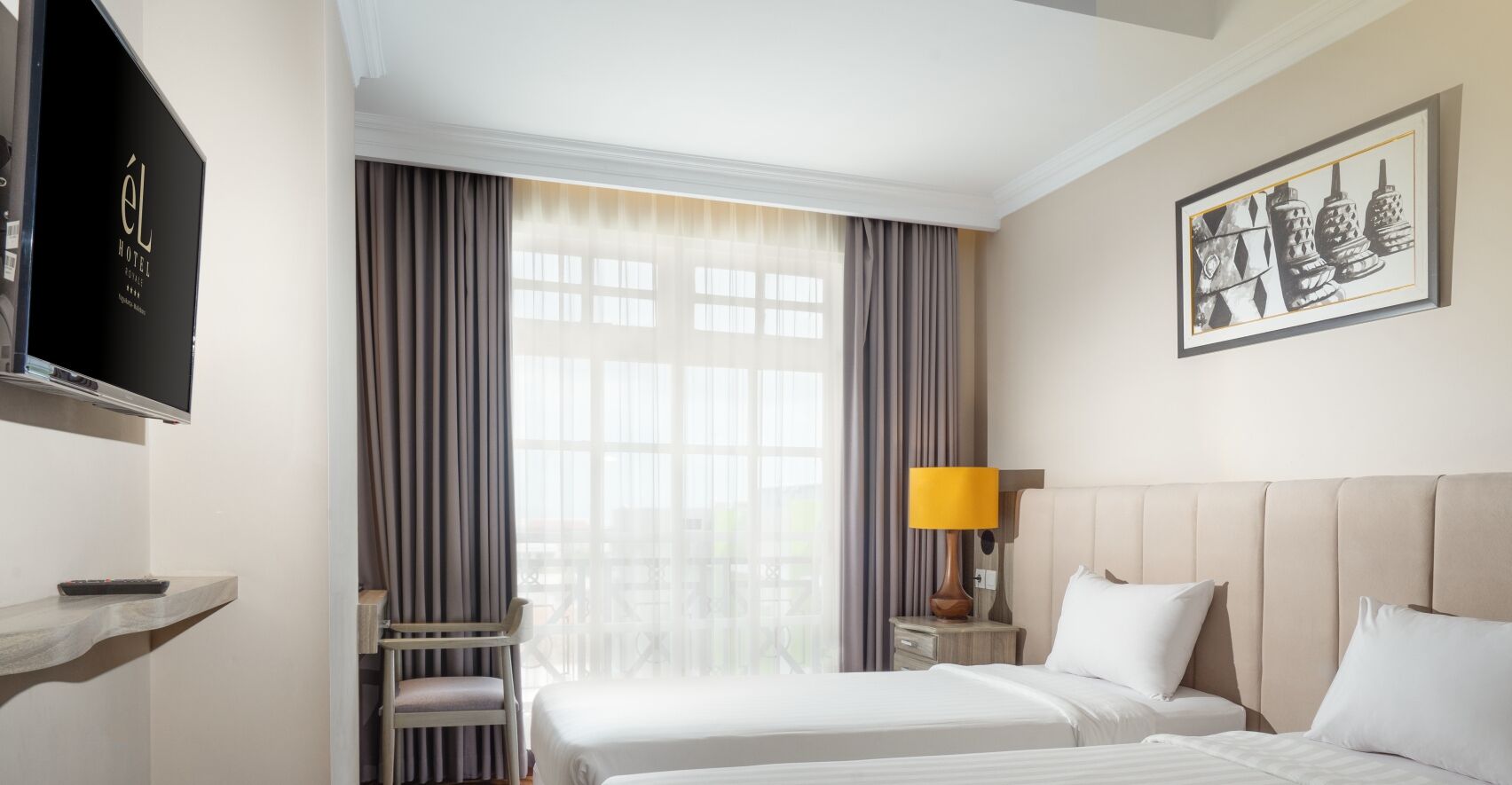 Ein Hotelzimmer mit Bett, Fernseher, Schreibtisch und einem Fenster mit Vorhängen.