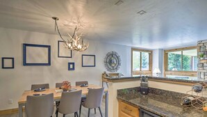 Una cocina moderna con encimeras de granito, lavavajillas y un comedor con mesa y sillas de madera.