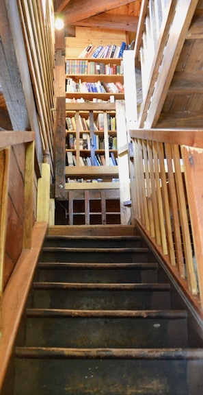 Staircase leads to a cozy library area with bookshelves and wooden beams.