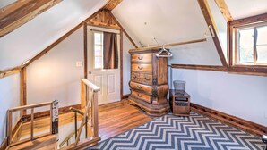 Una habitación con techo de madera, un aparador, una silla y un tapete estampado.