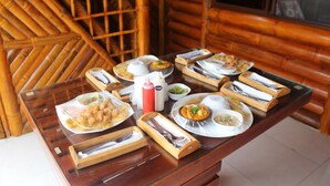 A dining table set with various dishes and utensils in a bamboo-themed room. - Soga Hostal (Santa Marianita)