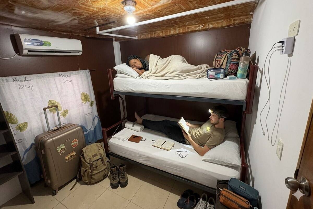 A bunk bed room with a suitcase, a backpack, and a pair of shoes on the floor.