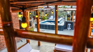 A pool area with lounge chairs, a small pool, and a thatched roof structure. - Soga Hostal (Santa Marianita)
