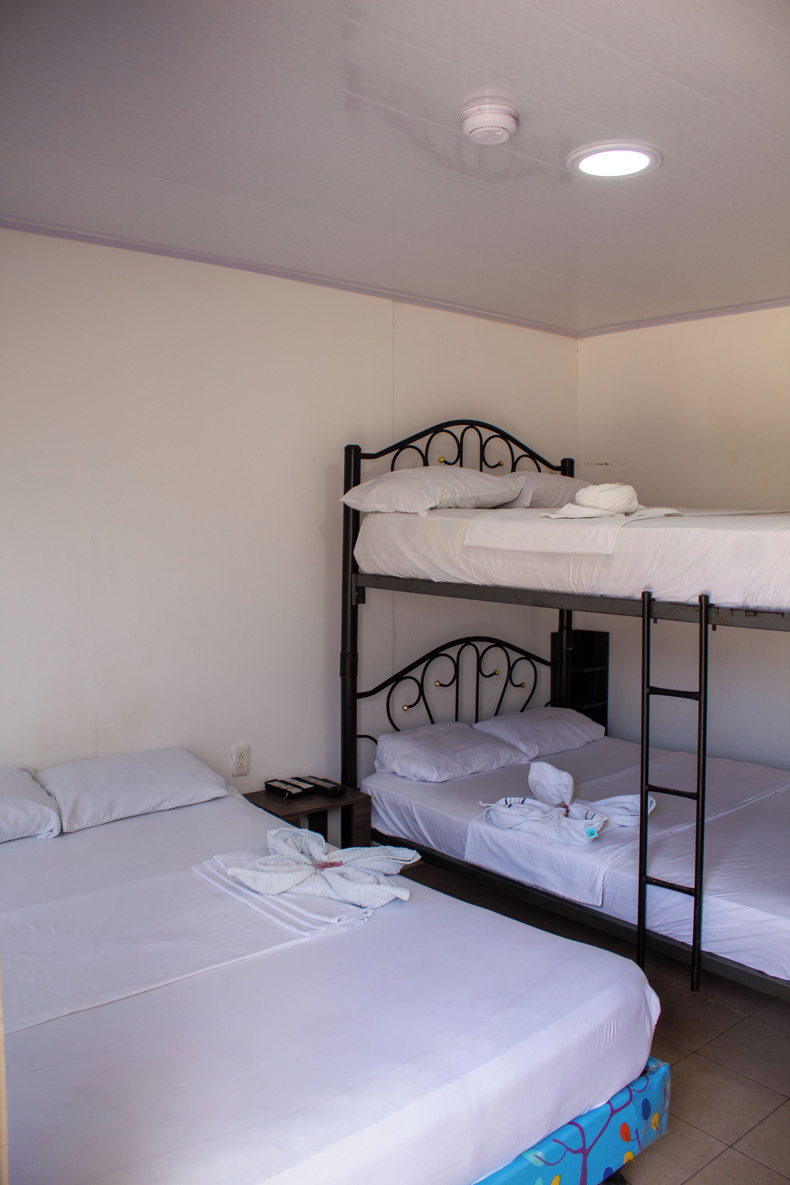 Une chambre avec un lit superposé, du linge de lit blanc et une petite table de chevet.
