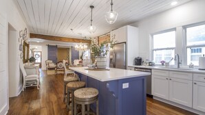 A modern kitchen with a central island, wooden flooring, and a large window providing natural light. - Charming Historic District Cottage Near Downtown (Conway)