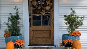 A wooden front door with a wreath, two lanterns, and two potted plants with pumpkins. - Charming Historic District Cottage Near Downtown (Conway)