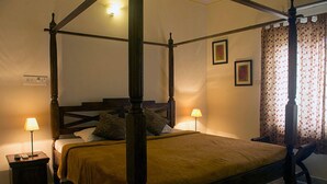 Un lit à baldaquin avec un cadre en bois, deux lampes de chevet et un rideau à motifs floraux.