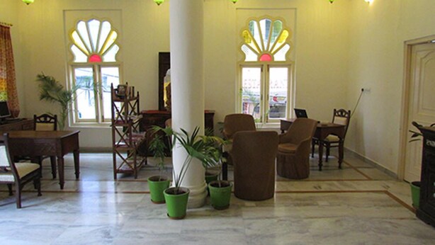 Un hall d’entrée spacieux avec un sol en marbre, plusieurs chaises, une table et des plantes en pot.