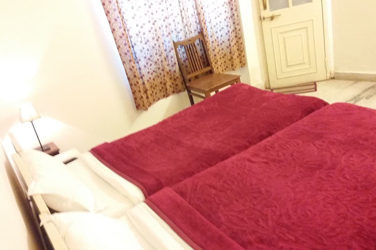 Une pièce avec un lit, une chaise, une porte et une fenêtre avec des rideaux.