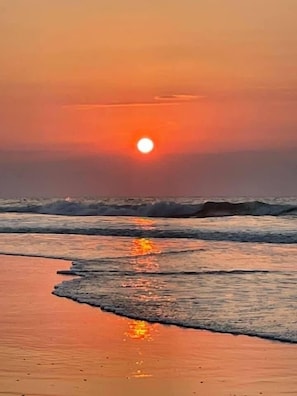 A sunset over a beach with waves.