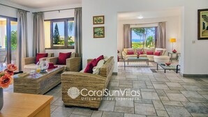 A spacious living area with wicker furniture, a glass coffee table, and a view of the outdoors. - Exceptional Large Villa, FREE HEATED Pool 1 NOV - 15 JAN, Privacy,Prime Location (Peyia)