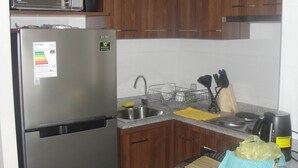Une cuisine de taille réduite, dotée d’un réfrigérateur en acier inoxydable, d’un four à micro-ondes et de meubles de rangement en bois.