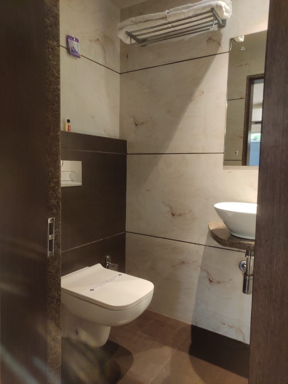 Un baño con inodoro, lavamanos y un perchero para toallas.